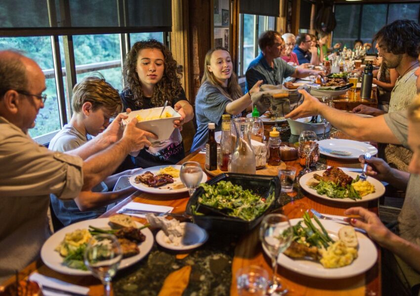 Many people eating food and conversing in a large dining room