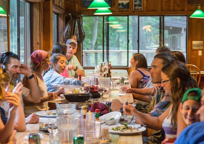 a group of people eating food in a rustic lodge on the Rogue River