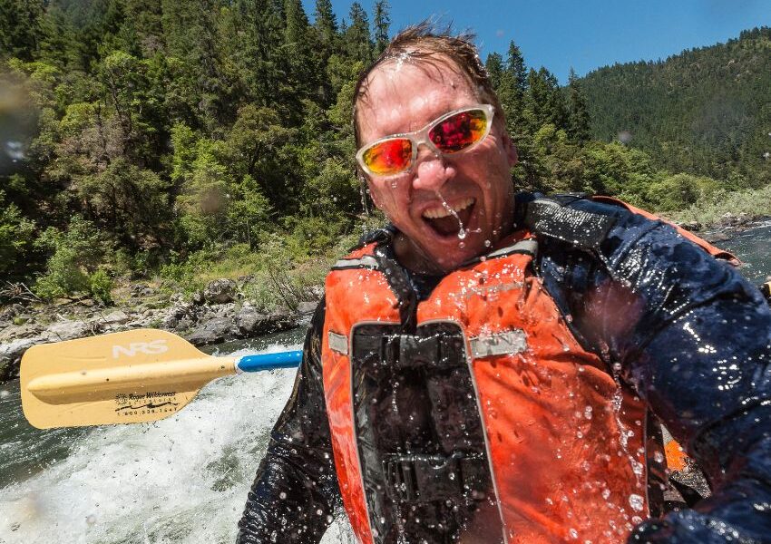 man is soaking wet while whitewater rafting