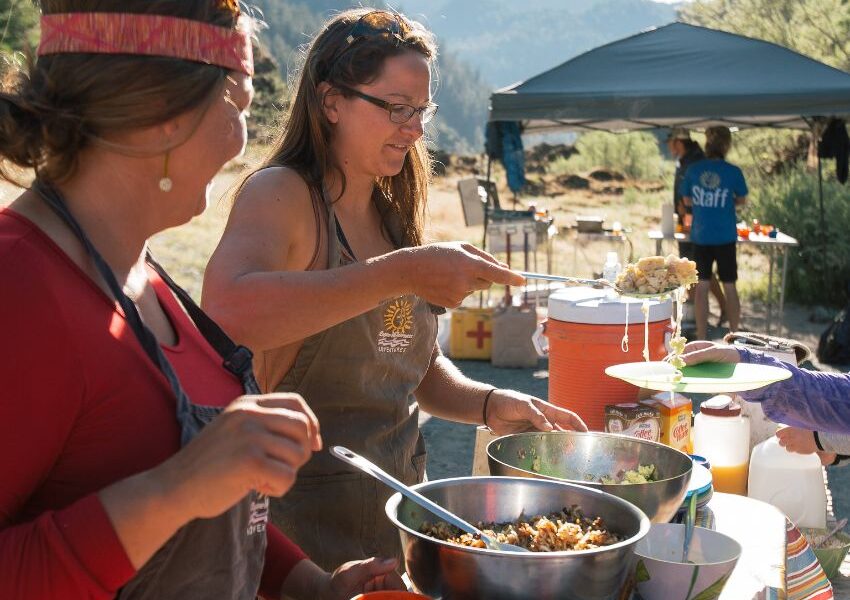 two women serving food at a riverside camp on the Rogue River