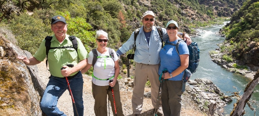 rogue river hiking trip a group of people smiling in front of the Rogue River in Oregon