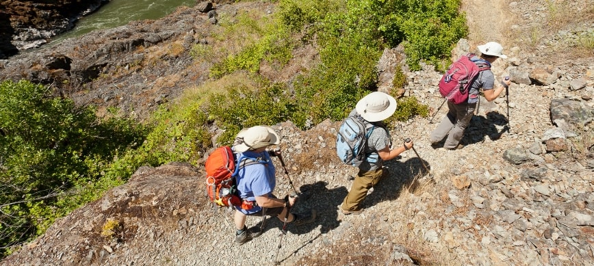 rogue river oregon hiking trail three hikers hiking on a dirt trail along a river