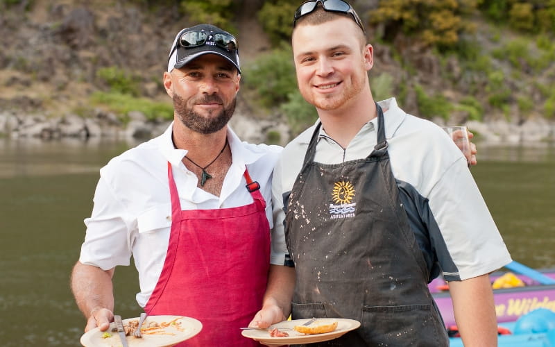 two men stand in front of a river