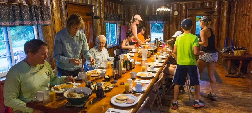 family rafting on the rogue river a group of people sharing a meal in a rustic lodge