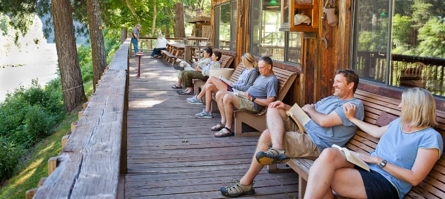 family rogue river rafting a group of people sitting on a porch above the rogue river