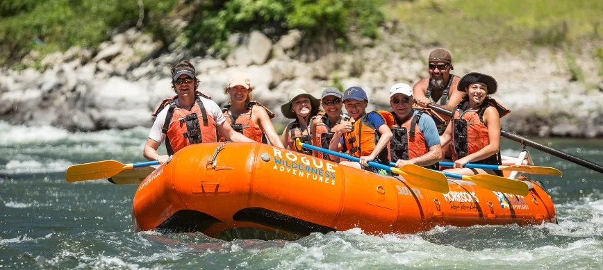 family whitewater rafting a group of people rafting on a river in an orange raft