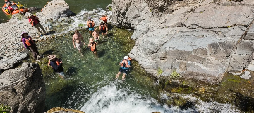 rogue river rafting for families a group of people sitting in a clear pool along a river